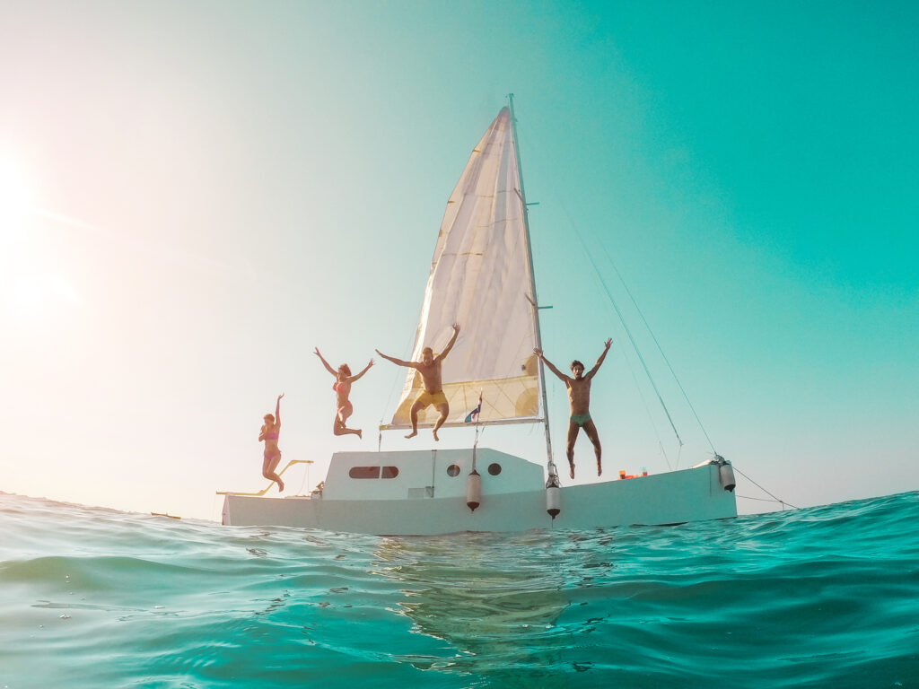 friends diving from sailing boat into the sea